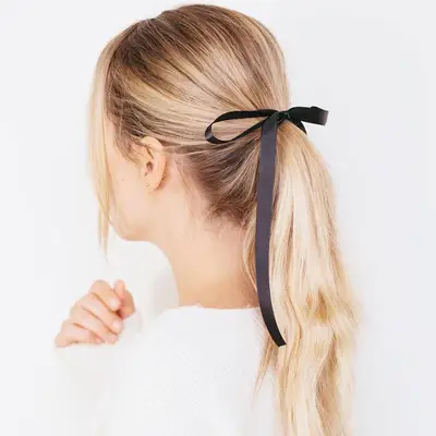 Long blonde low ponytail with thin black bow