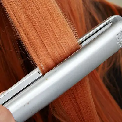 Close-up of a small section of hair being flat ironed