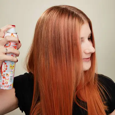Woman spraying her hair with shine spray