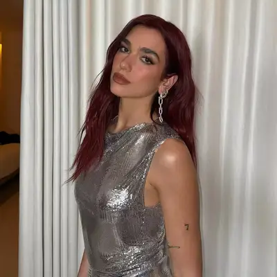 Dua Lipa with wavy, medium-length cherry cola colored-hair.