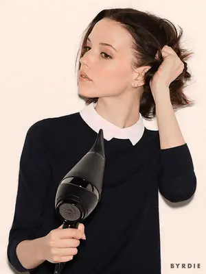 Close up of a model using a hair dryer to dry and scrunch her short brown bob.