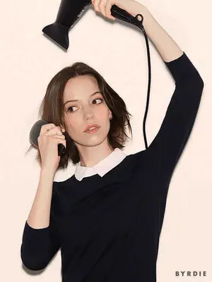 Close up of a model blow drying and brushing her short brown bob.
