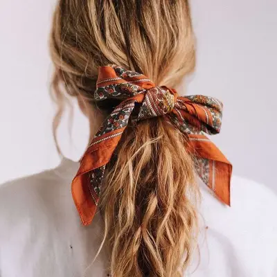 Back view of wavy hair tied into ponytail with orange floral bandana