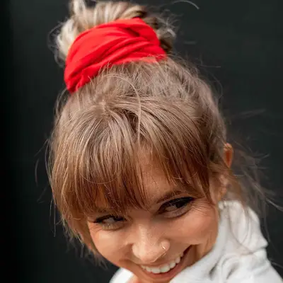 Woman with bangs and high bun wrapped with red scarf
