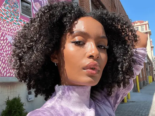 yara shahidi taking a selfie in purple shirt and curly hair