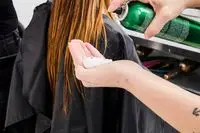 A person applies Redken Root Lifter Volumizing Spray Foam to the palm of their hand