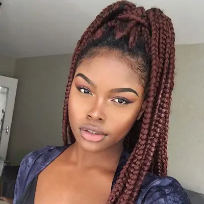 Woman with burgundy red box braids ponytail with dark roots