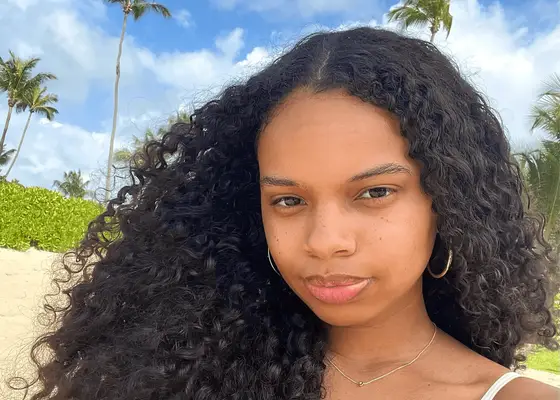 woman with moisturized scalp and curls on a beach