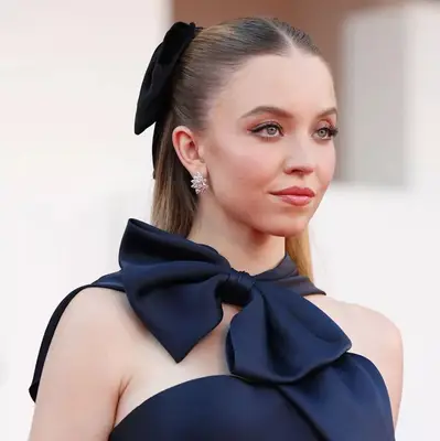 Sydney Sweeney attending an event, wearing an elegant outfit and featuring a bow accessory
