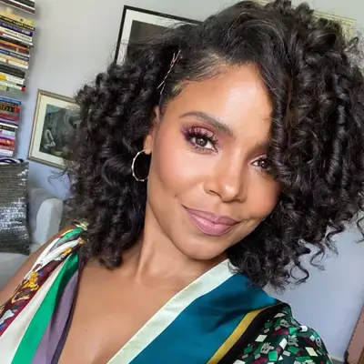 Sanaa Lathan hair styled in spiral set with side part and sparse gray strands 