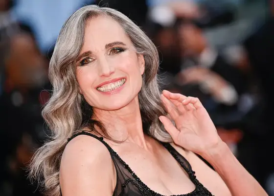Andie MacDowell with long gray hair in loose waves on the red carpet