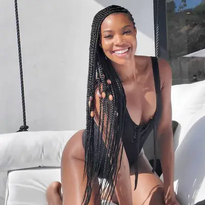 Gabrielle Union in a black one-piece bathing suit and side-parted box braids with brown beads