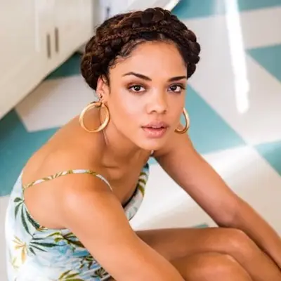 Tessa Thompson in a printed blue and green mini dress and brown braided crown hairstyle