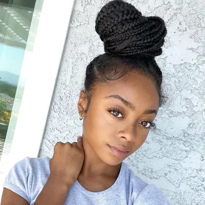 Skai Jackson wearing box braids in a high topknot bun