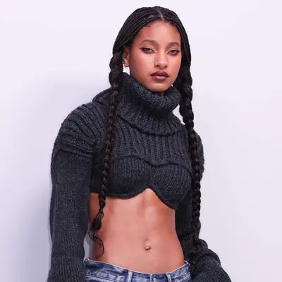 Willow Smith wearing a knitted crop top sweater and long box braids into two pigtails at the Acne Studios Fall/Winter 2024/2025 show at Paris Fashion Week