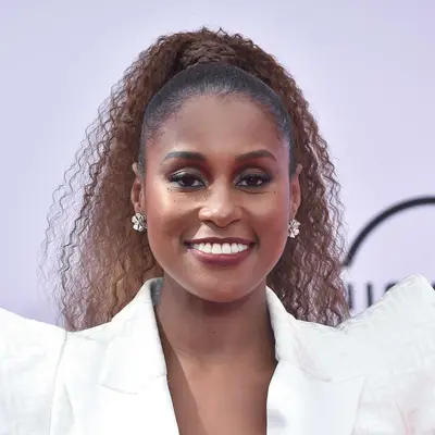 Issa Rae wears a high, naturally curly ponytail with a wrapped base