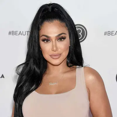 Huda Kattan wears a half-up high ponytail style with sleek, tousled texture