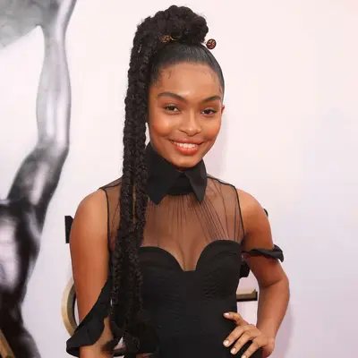 Yara Shahidi wears braids in a high ponytail with a gold hair accessory