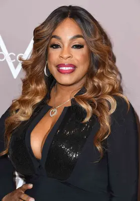 Niecy Nash dark brown hair with loose caramel-highlighted waves