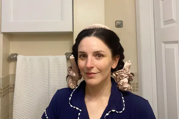 A person smiling and showing their hair wrapped with the Lilysilk Silk Curling Headband and Scrunchie Set