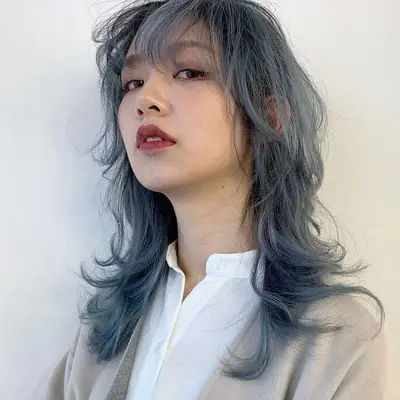 A model with ashy blue hair sports a brick-red lip