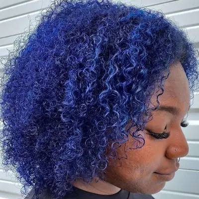 A young woman shows off curls with a navy blue hue