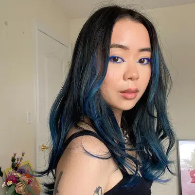 A young woman has blue and black hues mixed into her hair