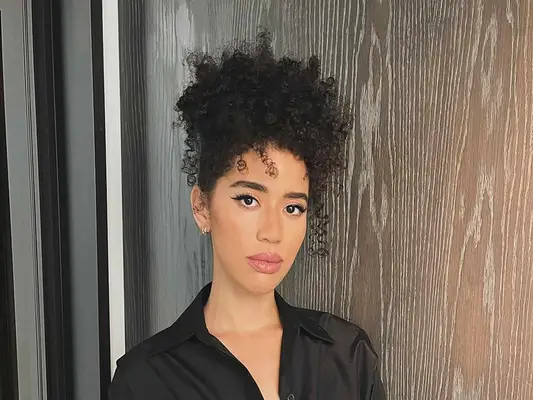 actor jasmin savoy with a curly natural hairstyle