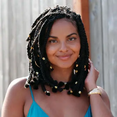 A woman with layered chunky box braids with gold beaded ends