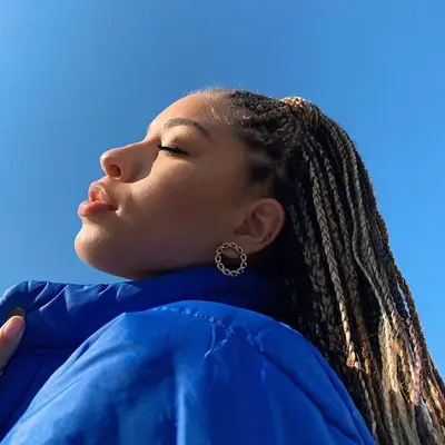 A woman with a mix of blonde and bronde box braids in a half-up, half-down 