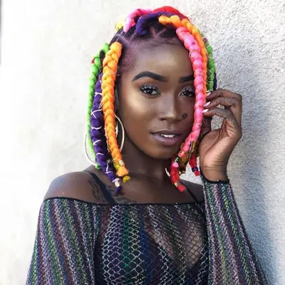 A woman with short, colorful rainbow and chunky box braids