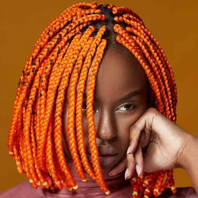 A woman with a bright orange, bob-length box braided hairstyle