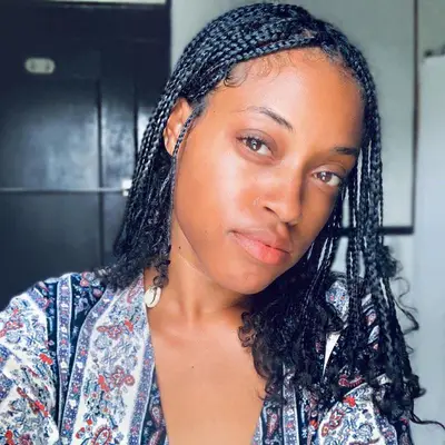 A woman with short, mini box braids and curled ends