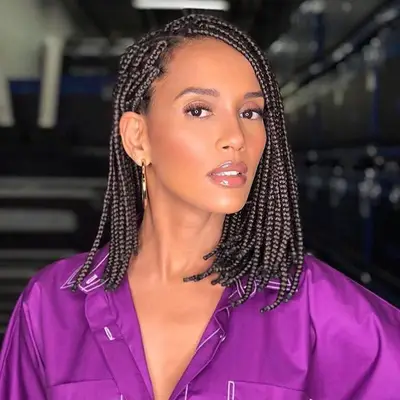 A woman with dark shoulder-length box braids with a side part