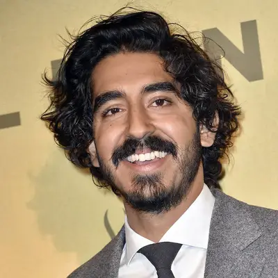 Dev Patel wears a tousled wavy side-swept hairstyle