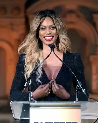 laverne cox standing at a podium with side swept hair