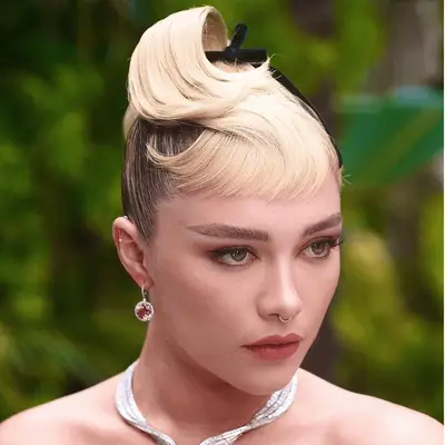 Lori Harvey with side-parted slick updo attends the 