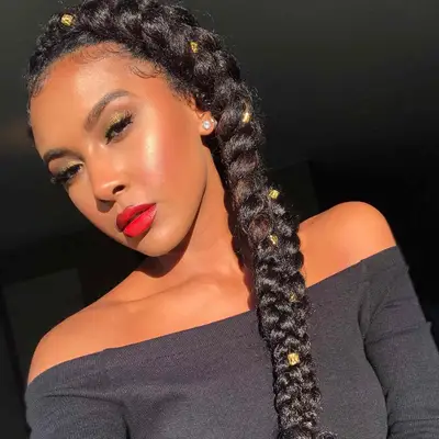 Woman with intricate side braid hairstyle adorned with gold charms