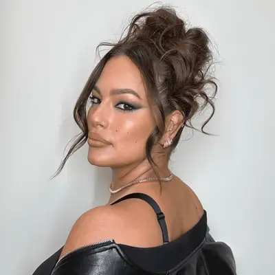 Ashley Graham with a tousled updo and face-framing tendrils.