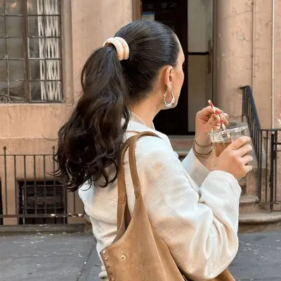 Model wearing a mid-head ponytail with a tan ponytail cuff. 