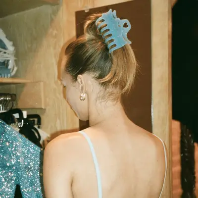 The back of a blonde-haired model with her hair in a large blue claw clip.