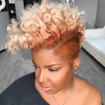 Woman with short, rose gold natural curls with platinum tips