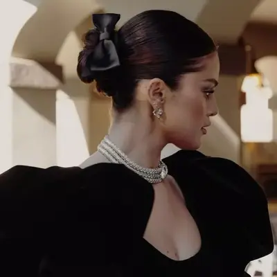 Selena Gomez wears a low bun with black ribbon