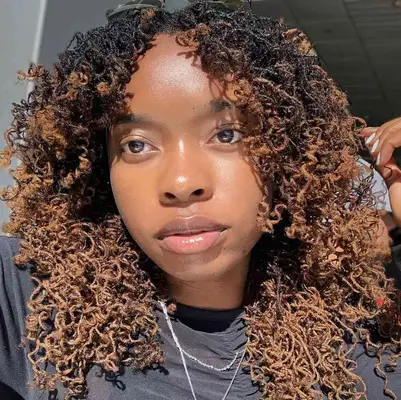 A person wearing black-to-brown ombré sisterlocs