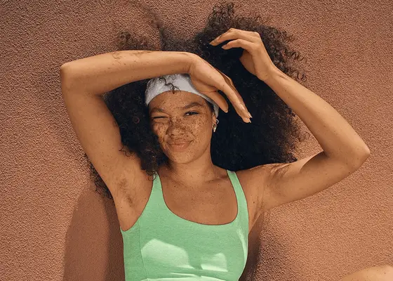 close up of woman wearing headband in curly hair on terracotta background