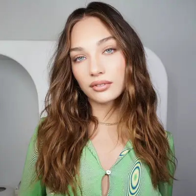 Maddie Ziegler with wavy chestnut hair and honey highlights.