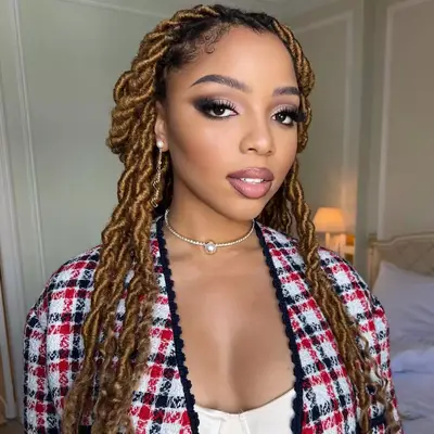 Chloe Bailey with copper warm blonde hair worn in twists.