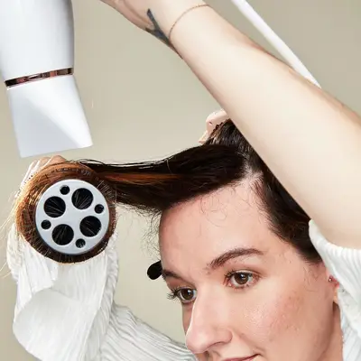 Model blow drying her hair with a round brush
