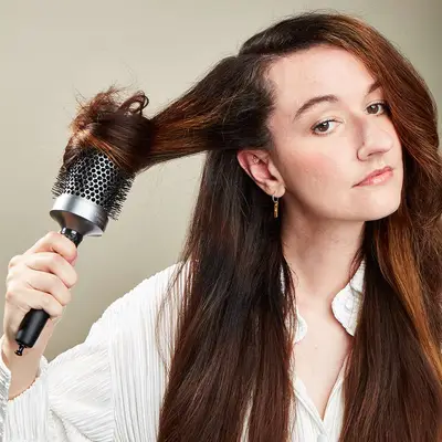 Model brushing the front of her hair with a round brush
