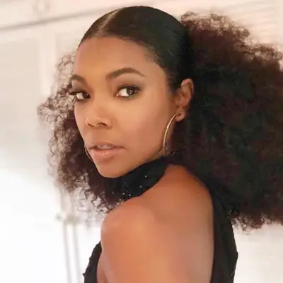 Gabrielle Union wears a middle part ponytail with sleek roots and Afro puff